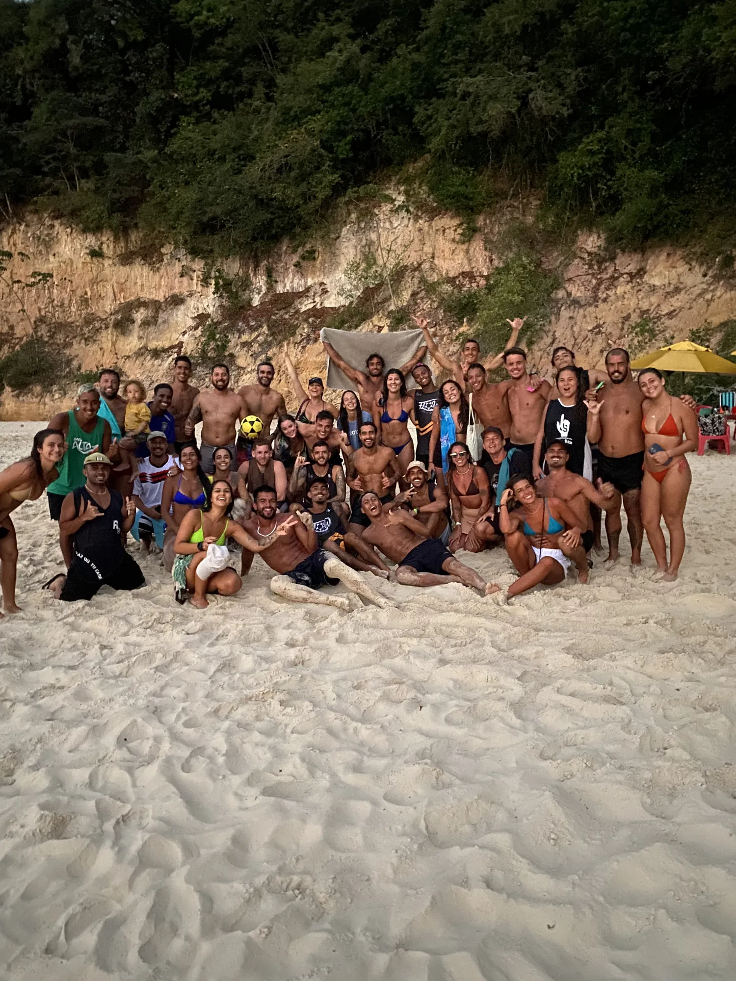 Grupo reunido na areia com a falésia de Pipa ao fundo