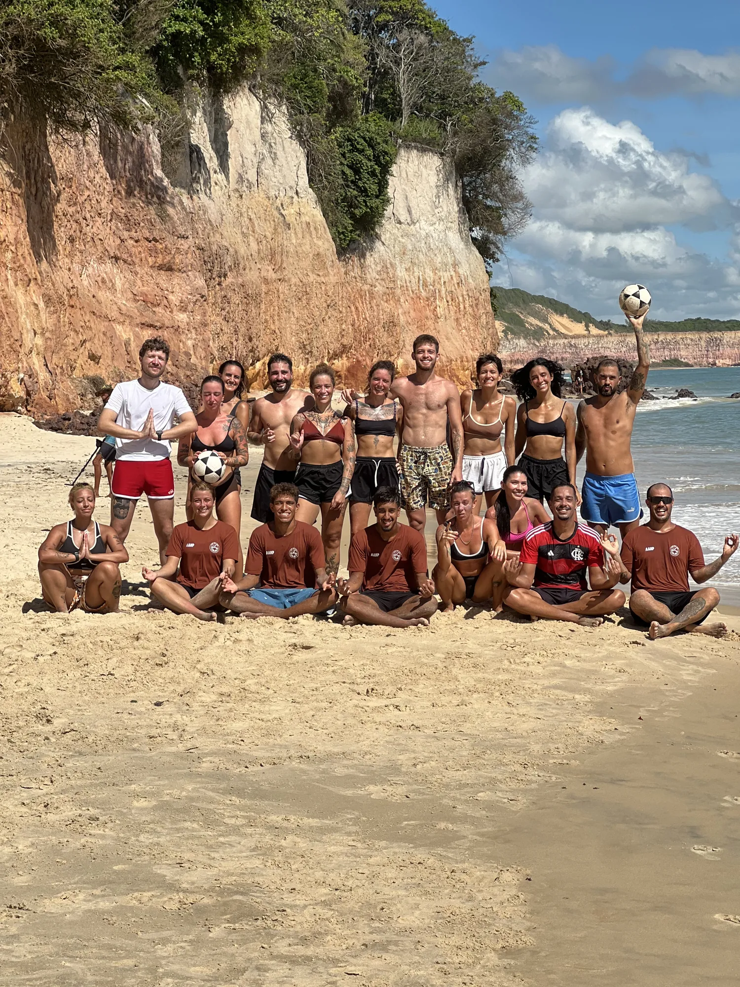 Alunos reunidos na areia ao sol com as falésias ao fundo