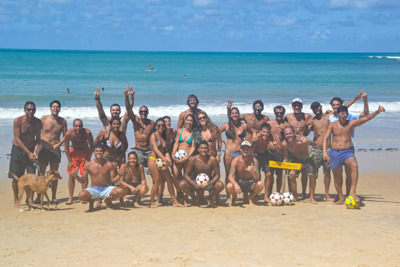 Galera da Alta comemorando junta na areia com o mar ao fundo